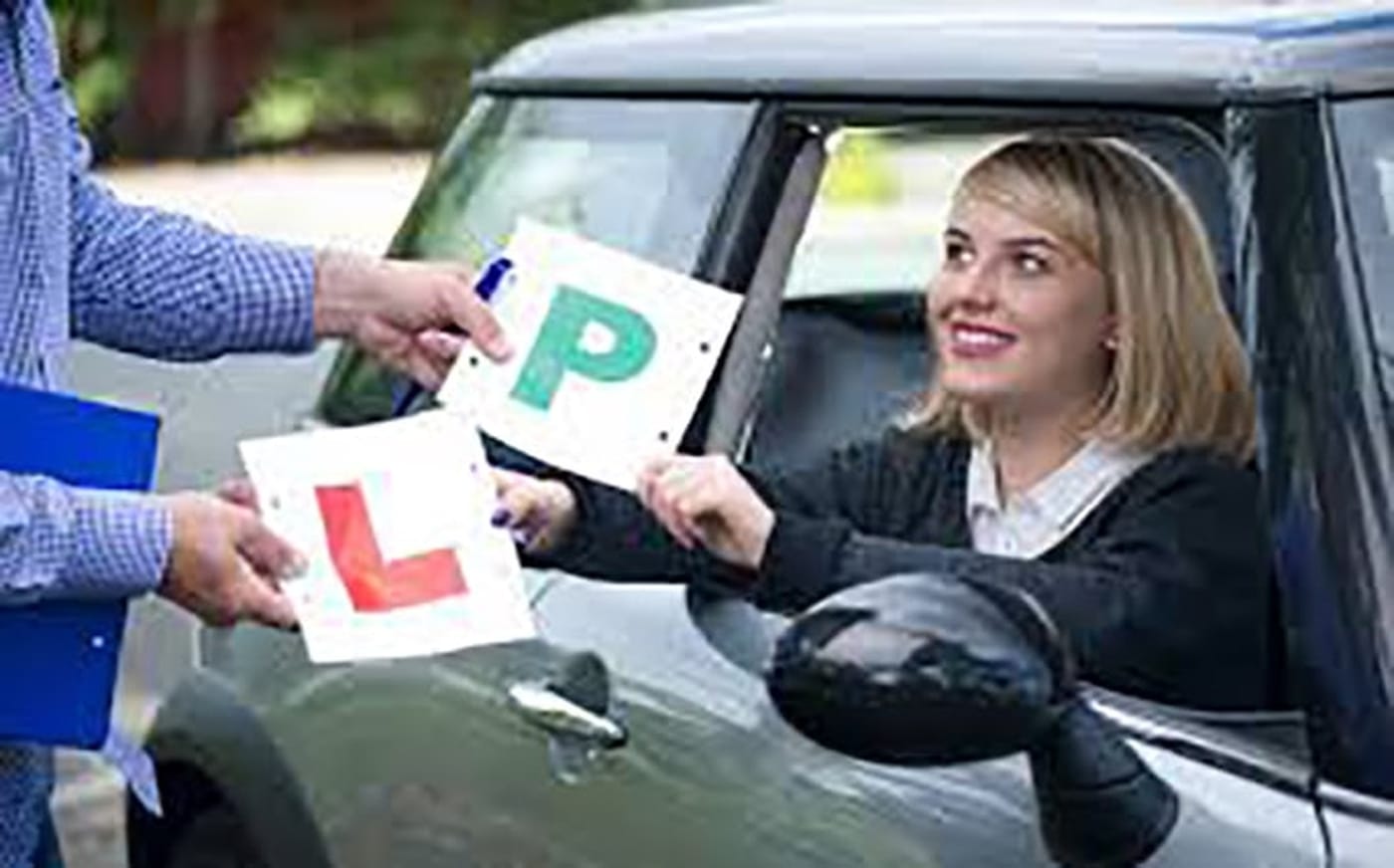 A driver being handed L and P plates through the car window